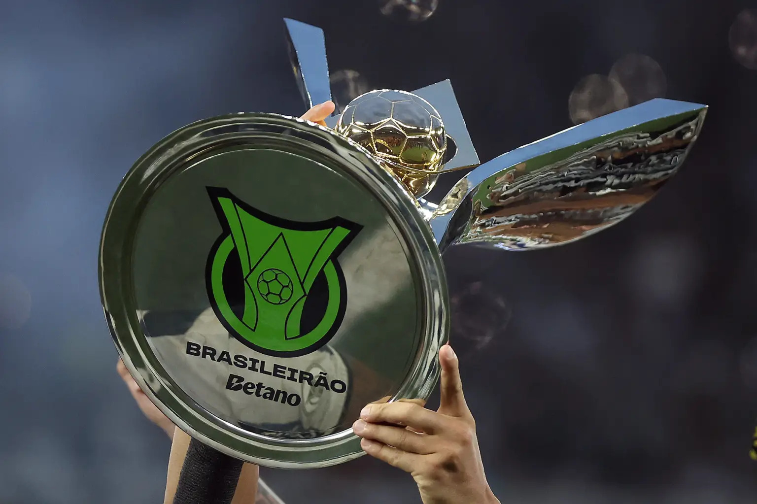 Troféu do Brasileirão sendo erguido, é possível ver embaixo do troféu escrito (Brasileirão Betano)