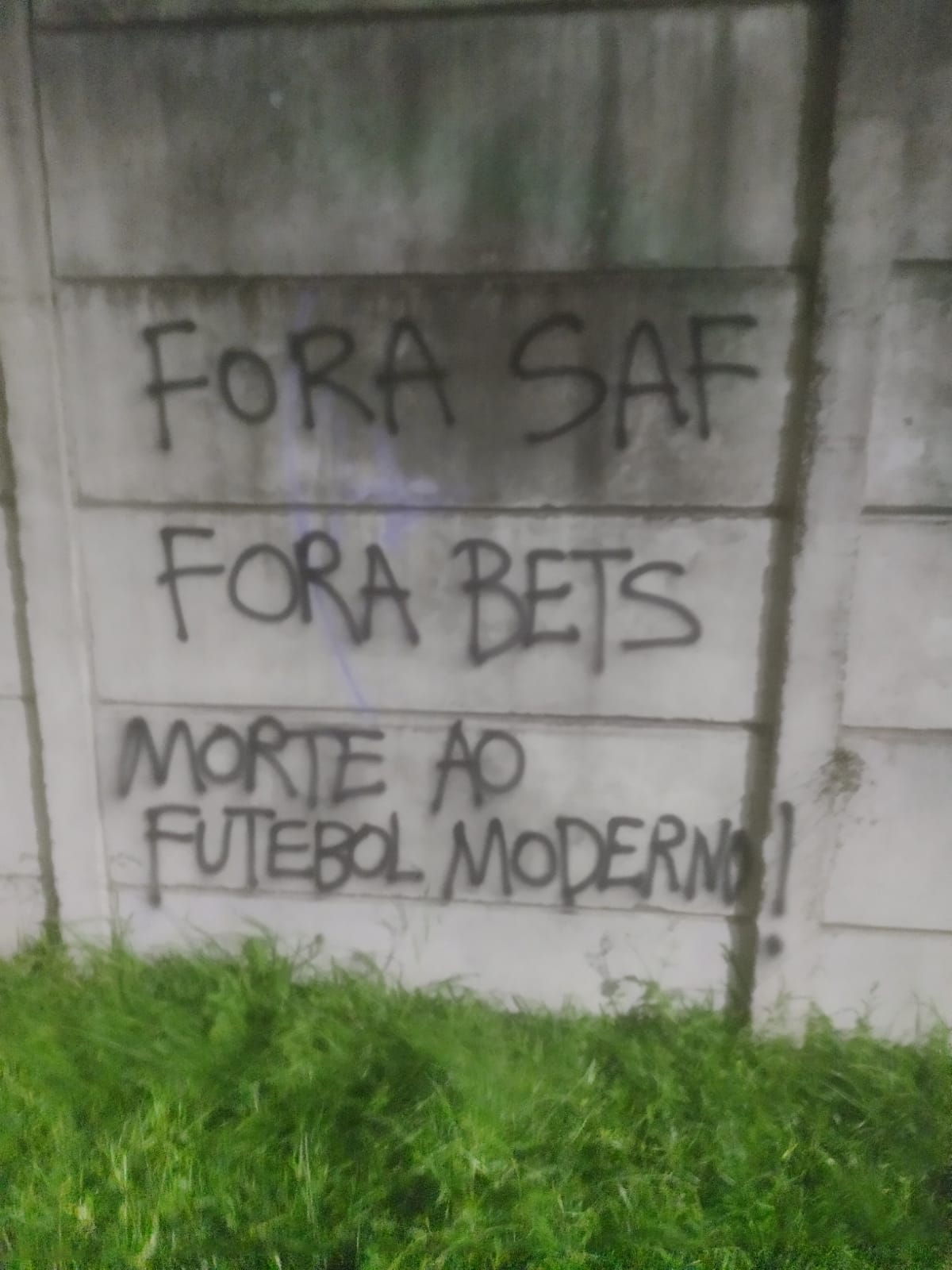 Foto de pixação em uma parede de concreto cinza: Fora SAF Fora Bets Morte ao Futebol Moderno!