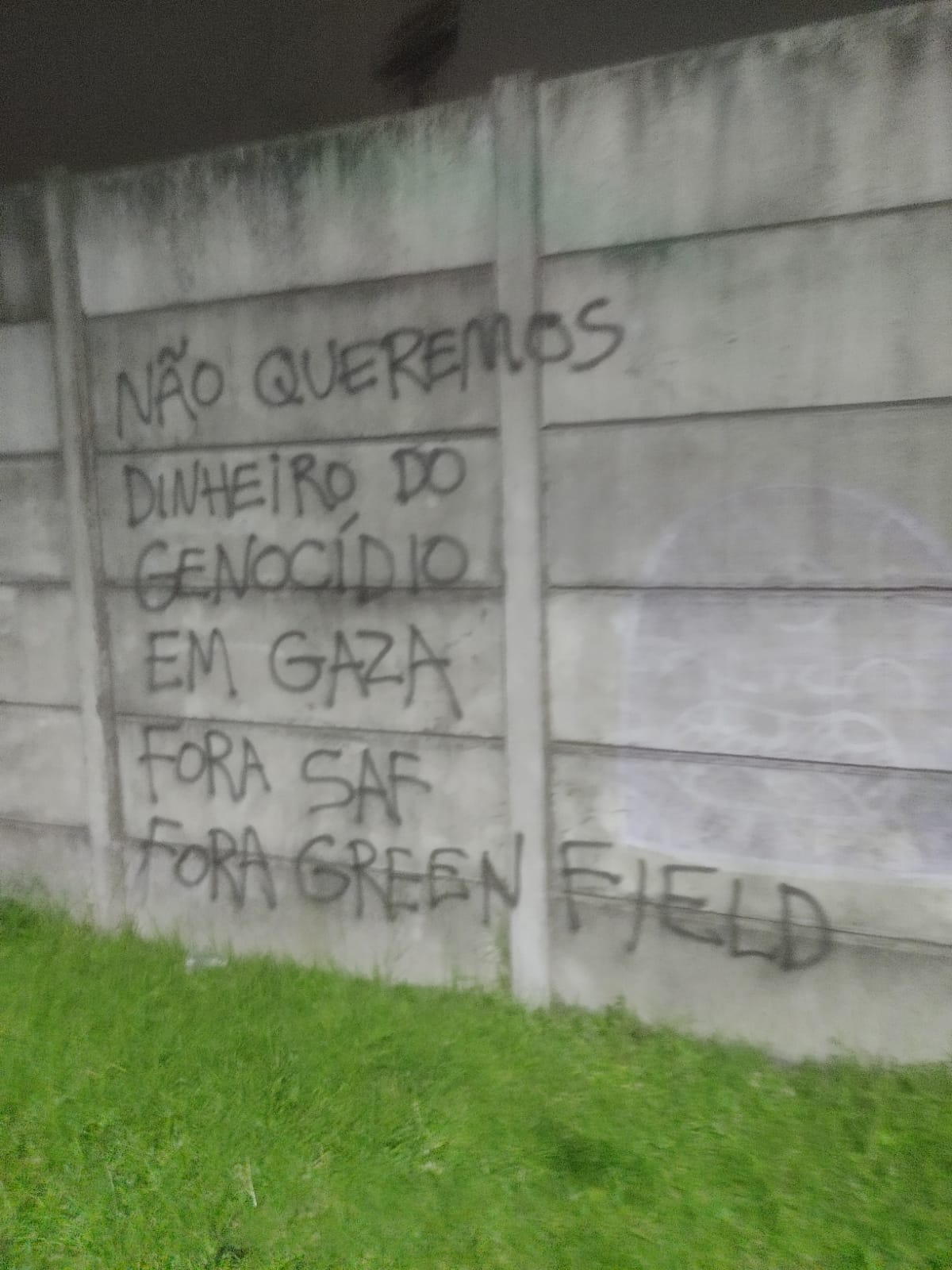 Foto de pixação em uma parede de concreto cinza: Não queremos dinheiro do genocídio em gaza fora SAF fora Greenfield