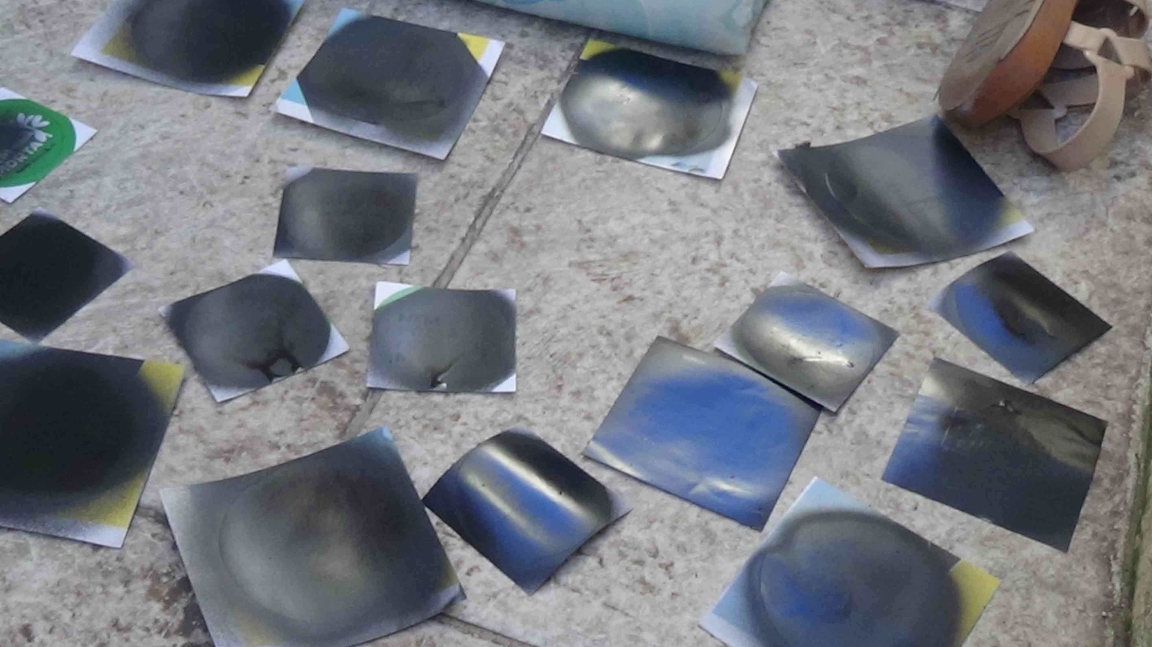 Foto de vários adesivos pintados de preto secando no chão.