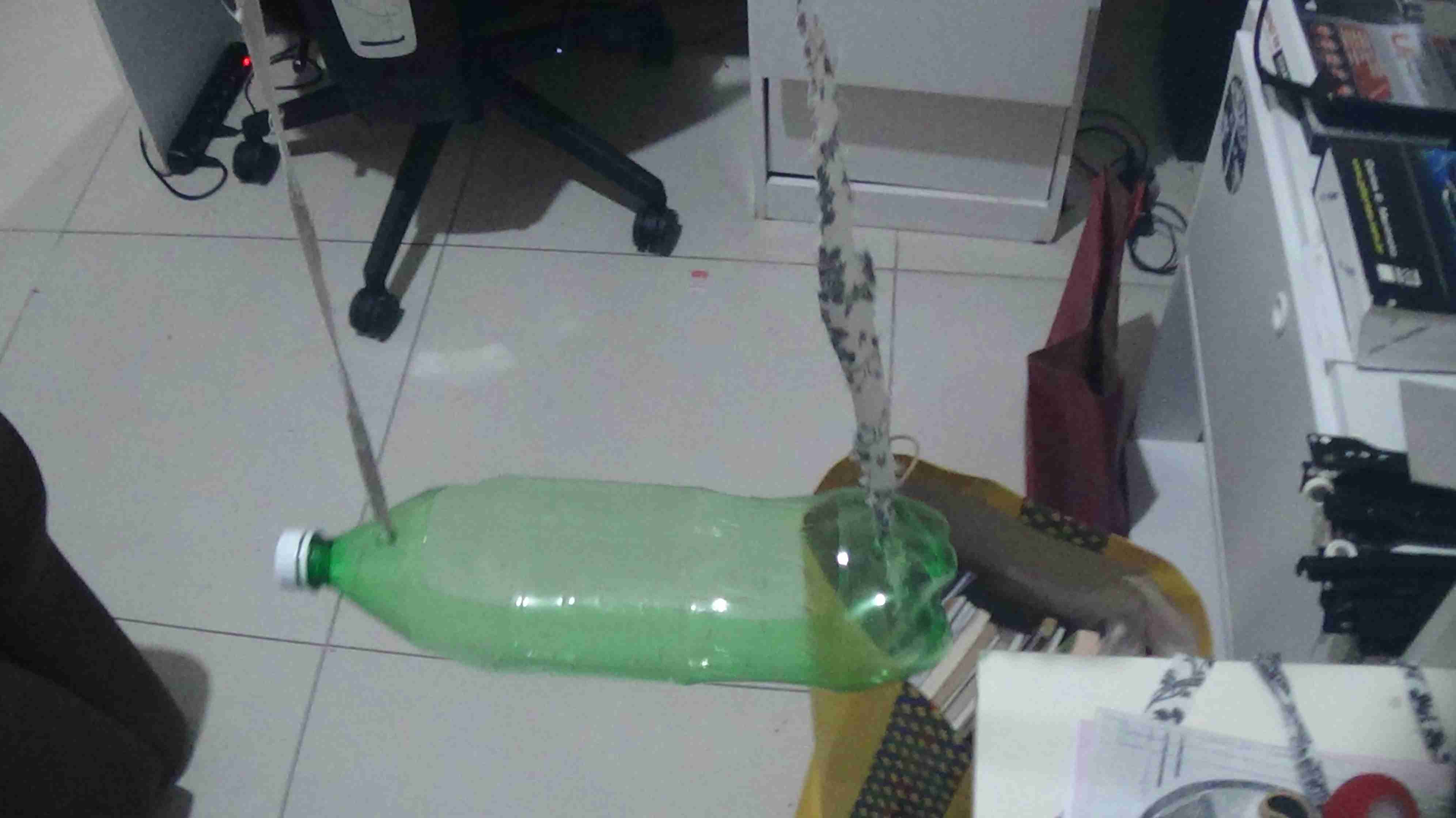 Garrafa pet na horizontal com dois fios sustentando ela no ar.