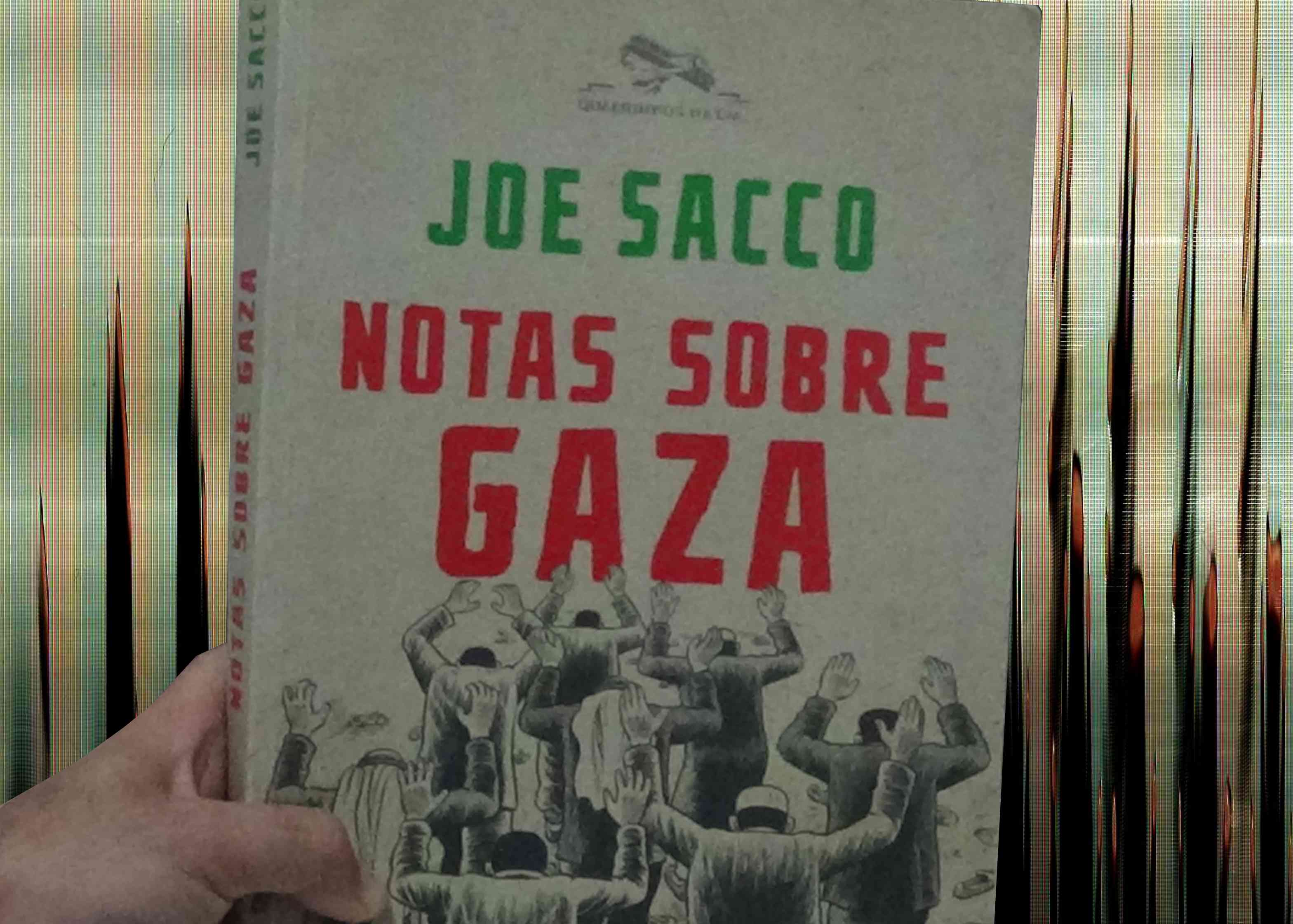 mão segurando um quadrinho grande, na capa está escrito: Joe Sacco   Notas Sobre Gaza    ilustração de 8 homens palestinos com as mãos para cima fazendo rendição ao lado de vários sapatos perdidos.