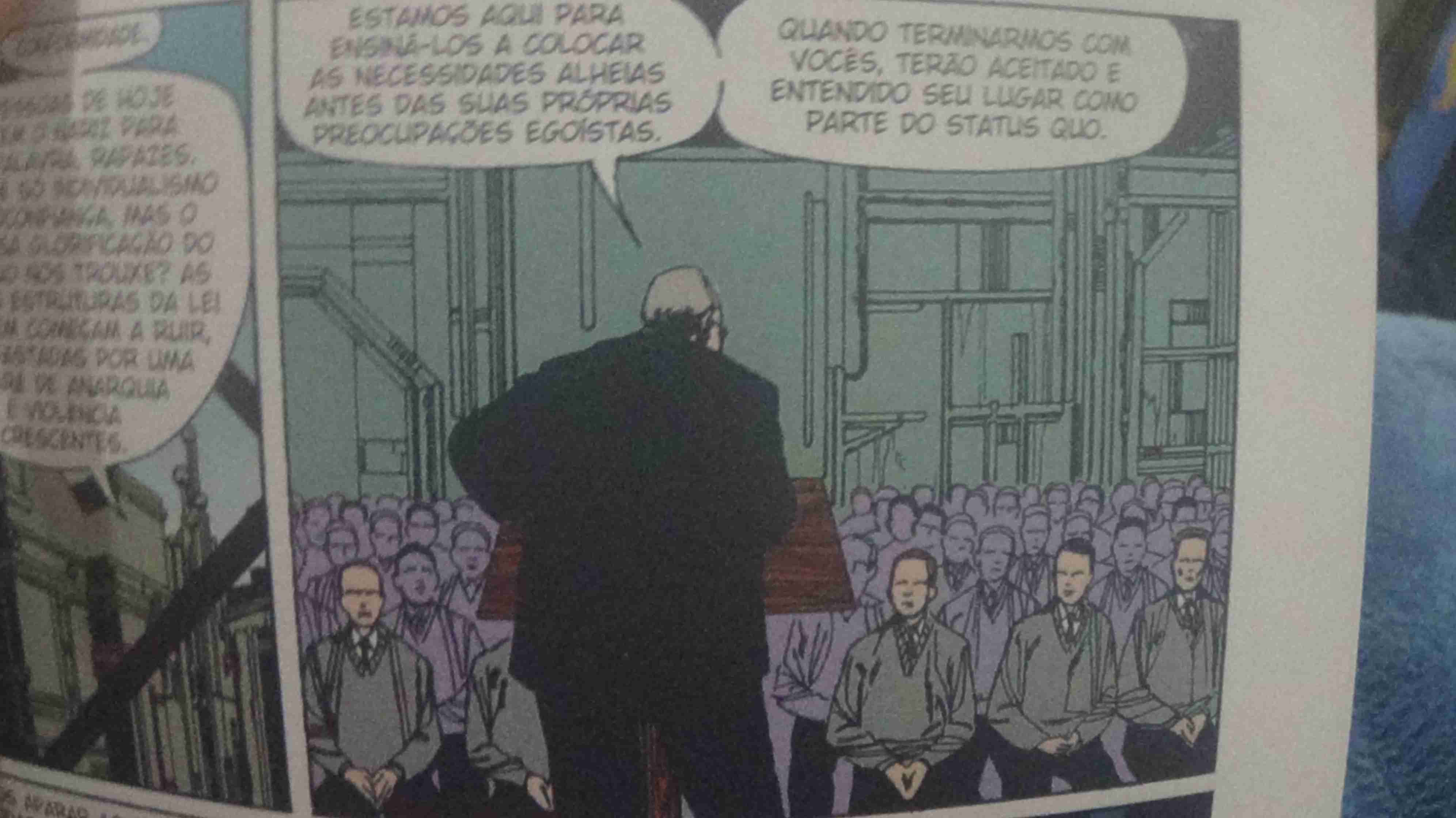Um diretor em um palanque diz para várias pessoas uniformizadas de cinza -Estamos aqui para ensiná-los a colocar as necessidades alheias antes das suas próprias preocupações egoístas. -Quando terminarmos com vocês, terão aceitado e entendido seu lugar como parte do status quo.